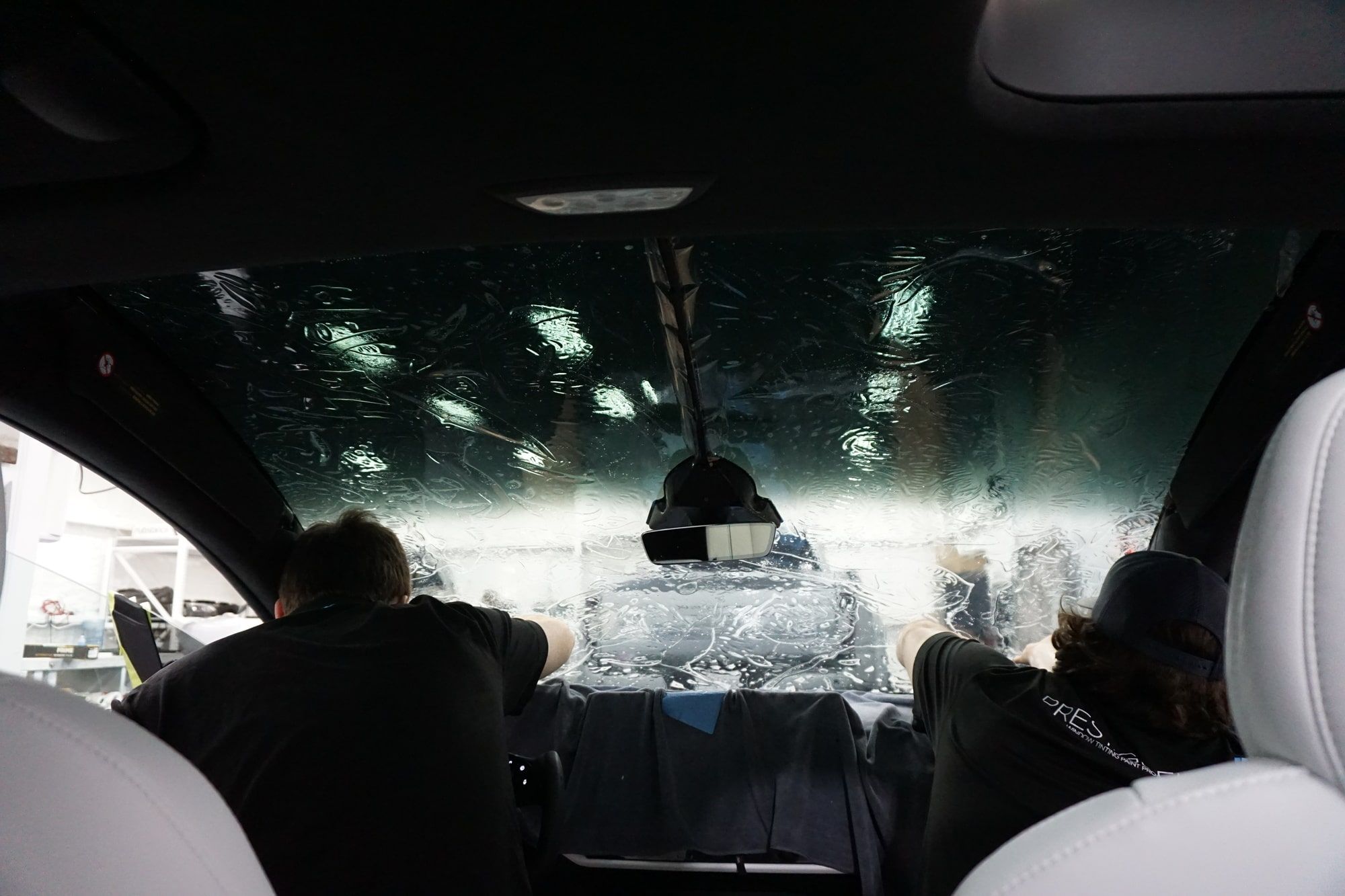 Installers applying window tint to a Tesla rear window