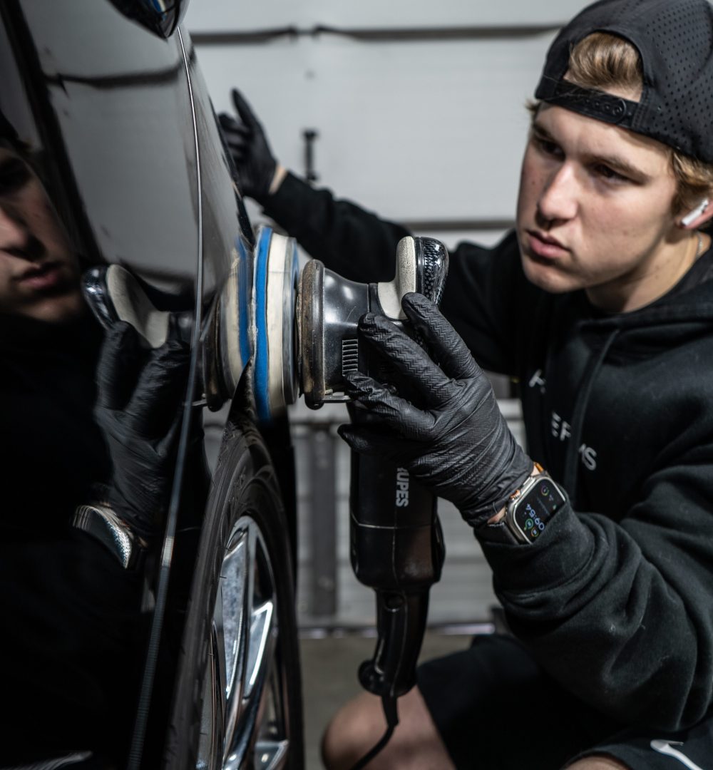 A detailer polishing a black vehicle at Prestige Films in Lafayette La.