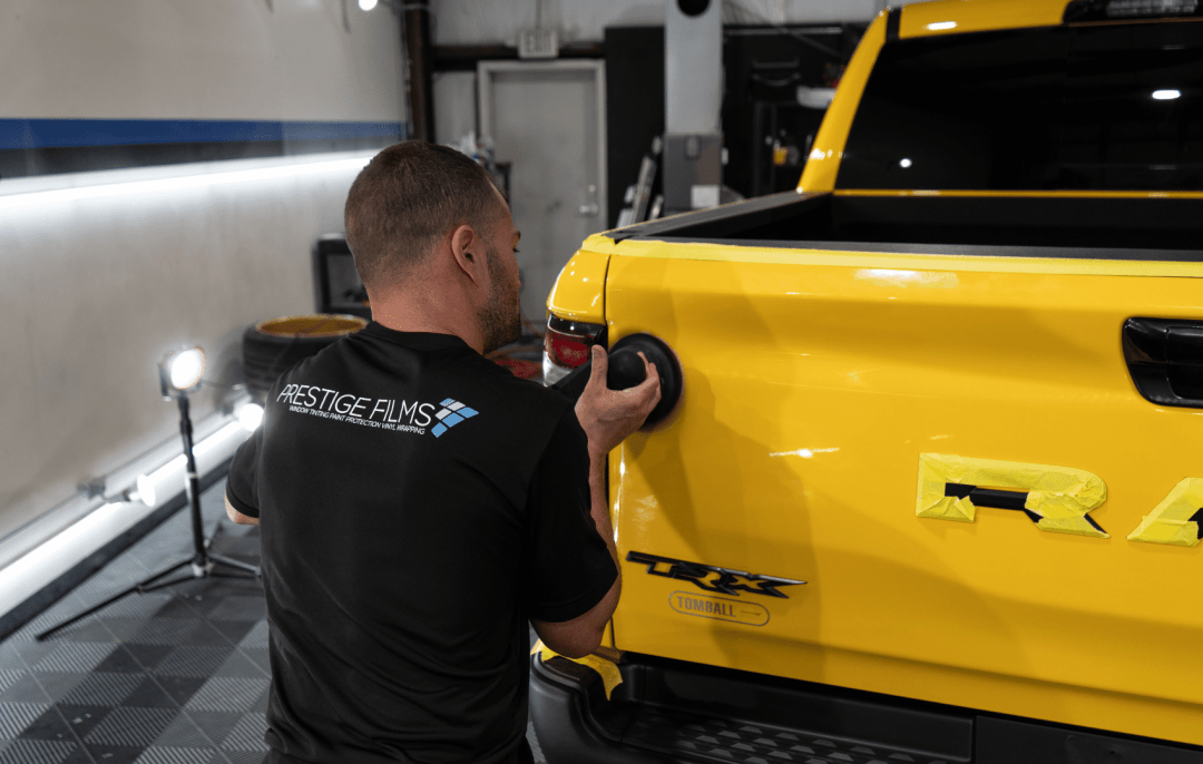 A detailer meticulously polishes a yellow truck at Prestige Films in Lafayette, Louisiana.