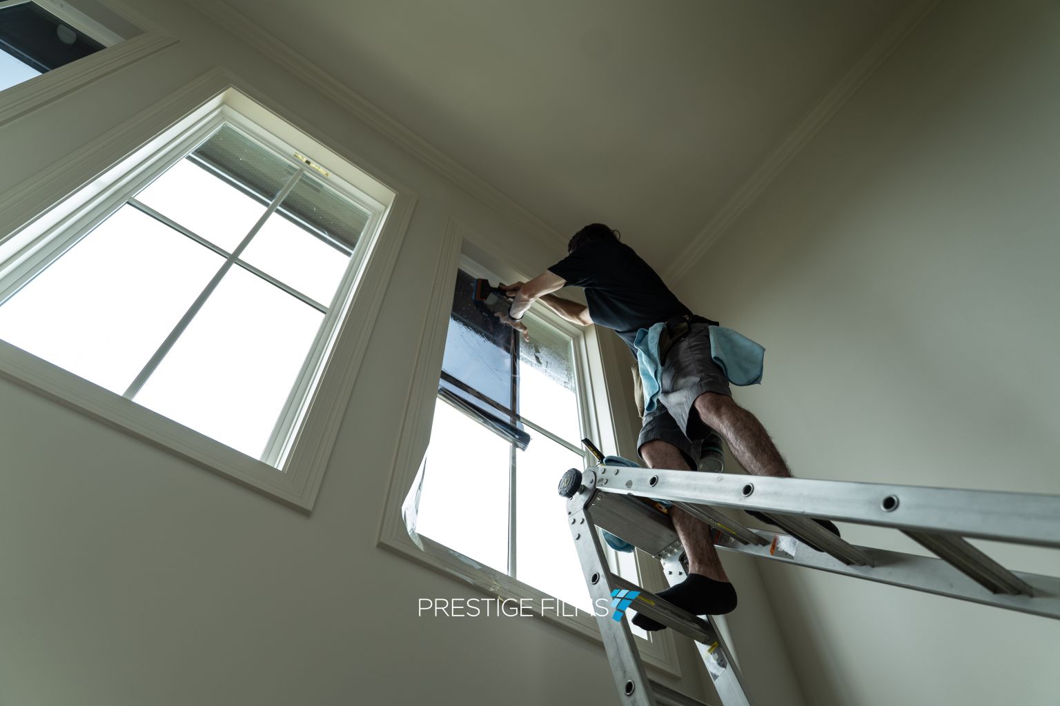Installer on a ladder applying window film to a clerestory window