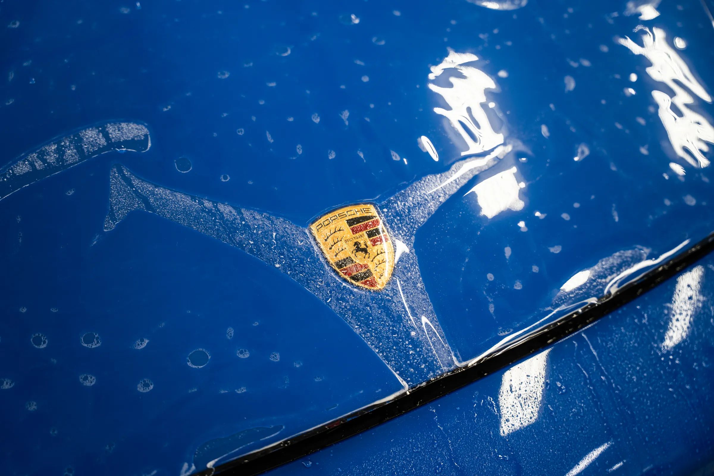 Paint protection film being installed on a blue Porsche hood.