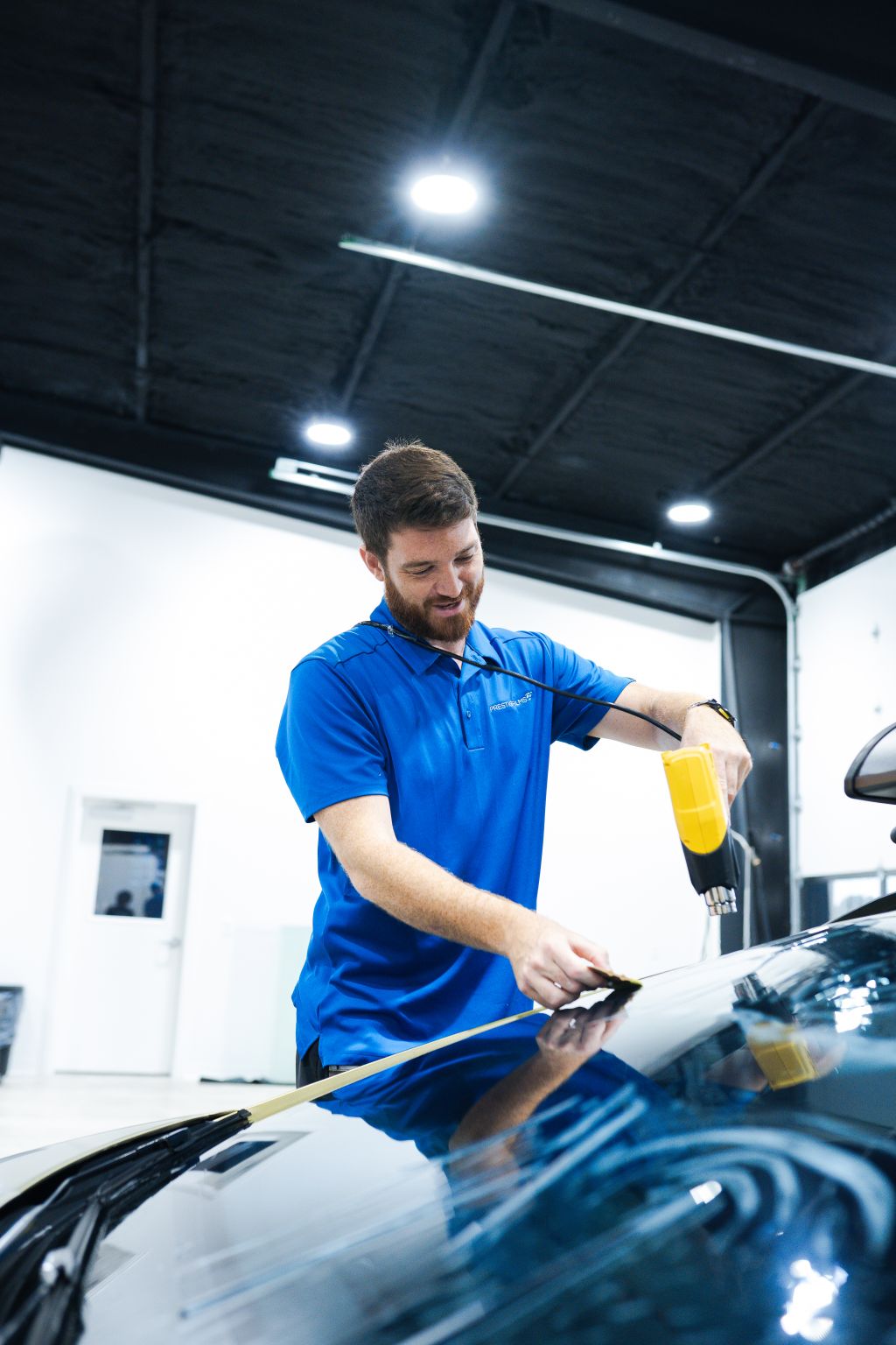 Prestige Films installer heat-shrinking ceramic window tint film on a car's back glass in the Lafayette shop