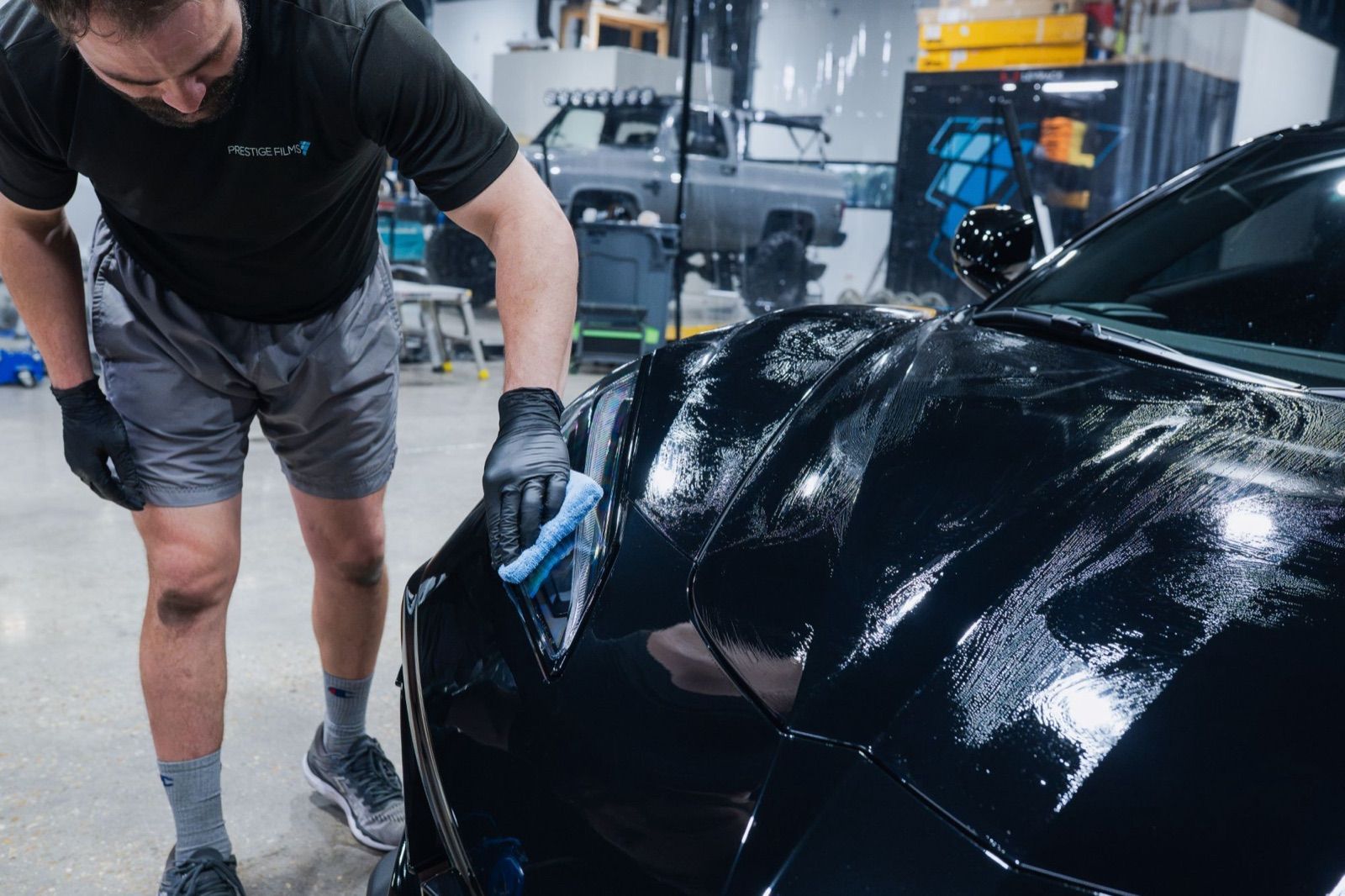 Technician applying XPEL FUSION PLUS ceramic coating to the front of a black car
