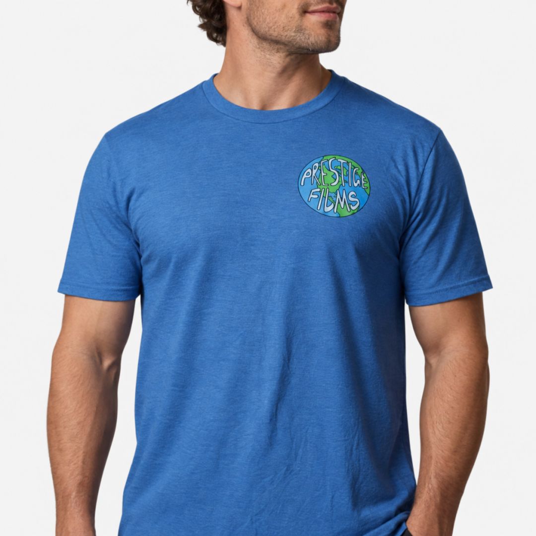 Blue crew-neck T-shirt with a small circular globe logo on the left chest reading 'Prestige Films'.