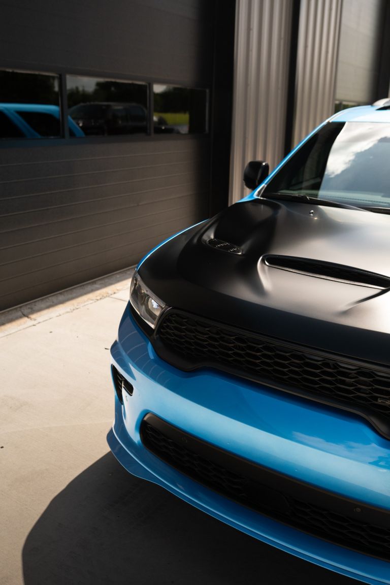 Front bumper, grille and hood of a blue Dodge Durango with paint protection film