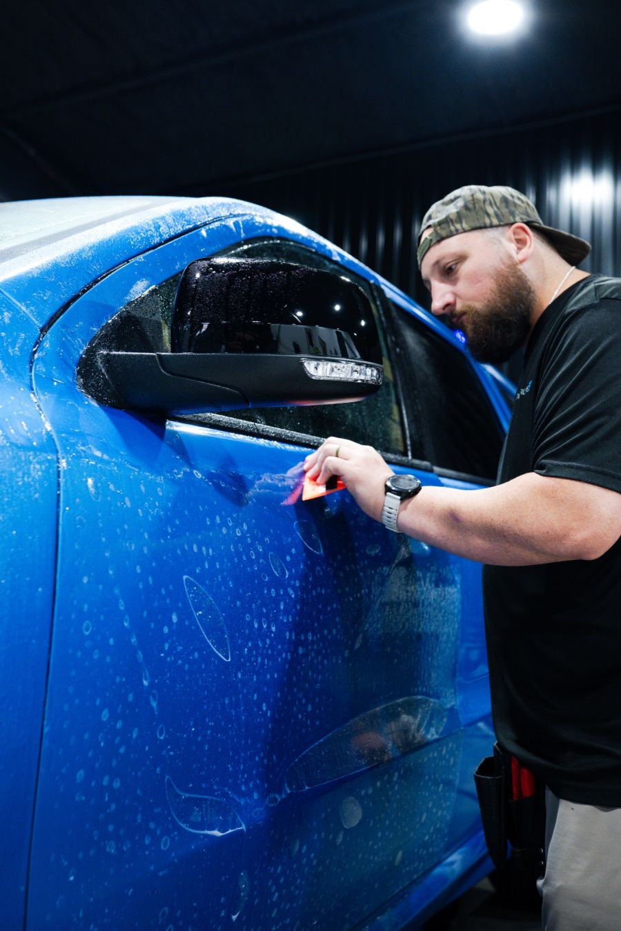 Installer applying paint protection film to a blue truck
