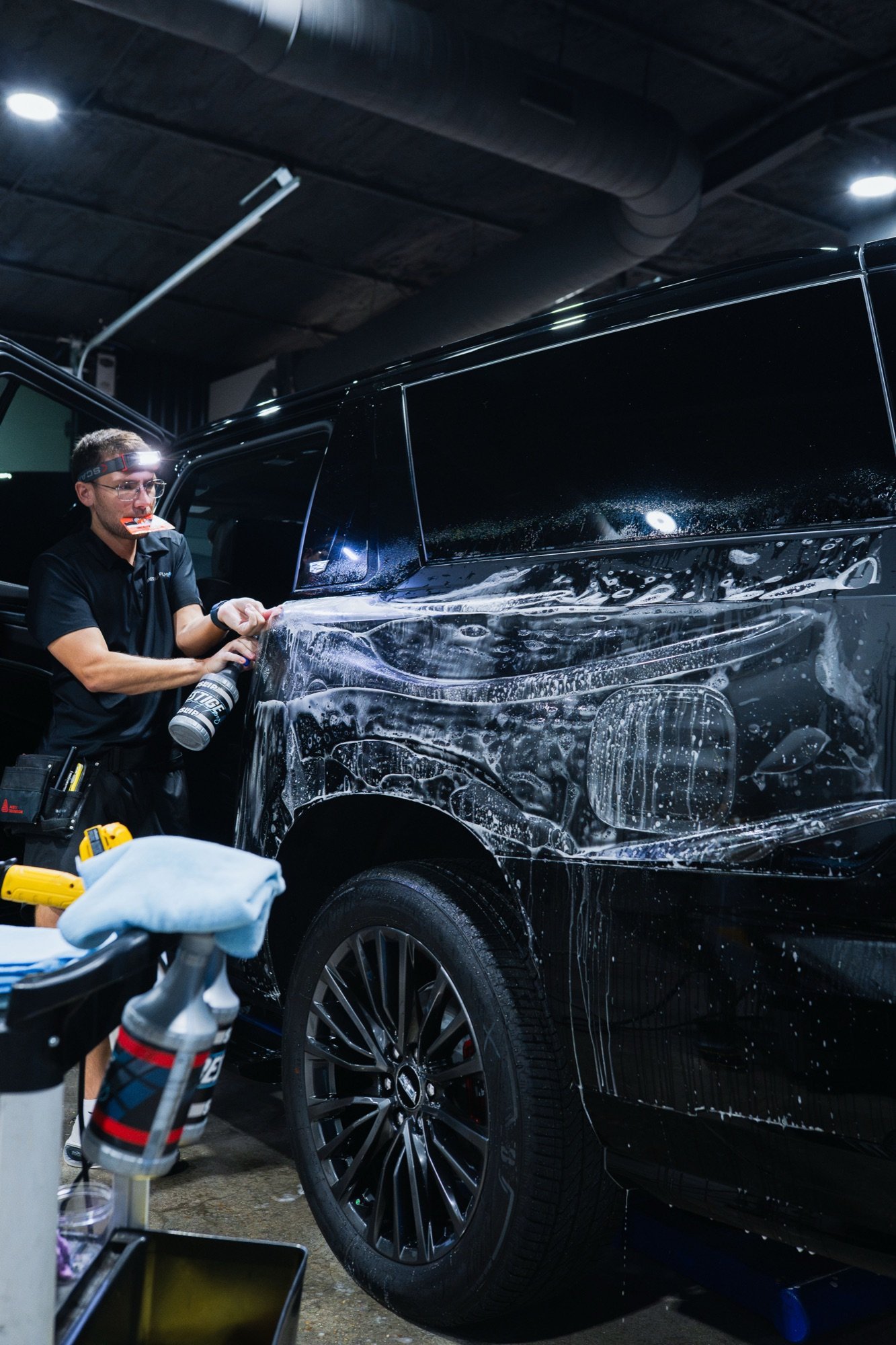Prestige Films installer laying XPEL Ultimate Plus paint protection film on a black Cadillac Escalade